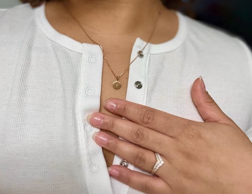 Reviewer's close-up of the gold DAINTY CHAIN NECKLACE styled with a round charm.