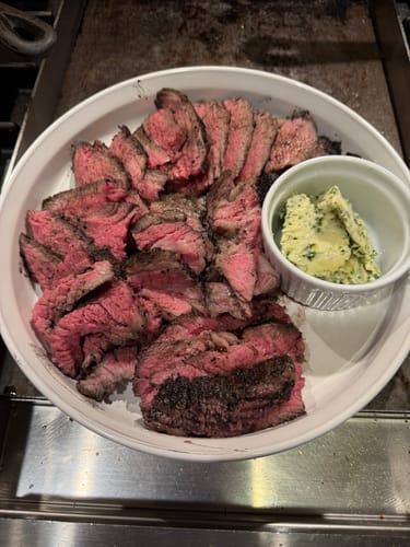 Customer's sliced USDA Choice Tri-Tip Steak on a white plate with a side of blue cheese compound butter.