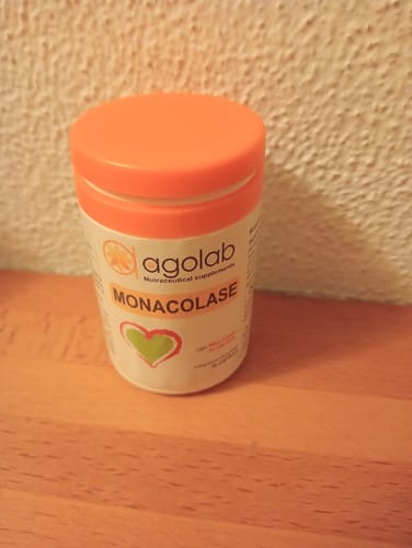 Recensione del cliente: il flacone di Monacolase con un tappo arancione, appoggiato su un tavolo di legno.