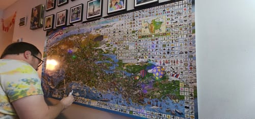 Customer marking an item on the large World's Greatest Search & Discover USA Edition poster on a wall.