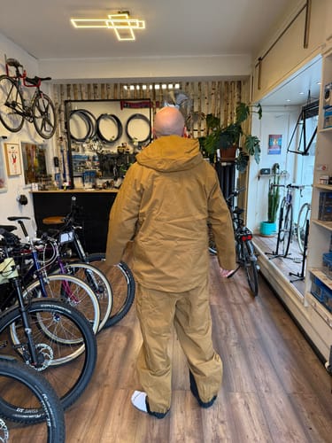 Reviewer from behind wearing the baggy Timber Tan Insulated Snow Pants and matching jacket indoors.