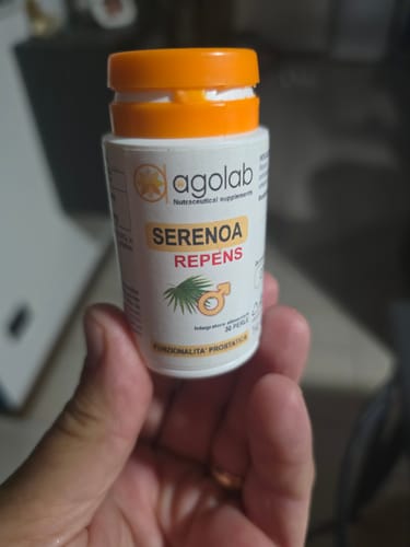 Un recensore tiene in mano il flacone bianco con tappo arancione dell'integratore Serenoa Repens.