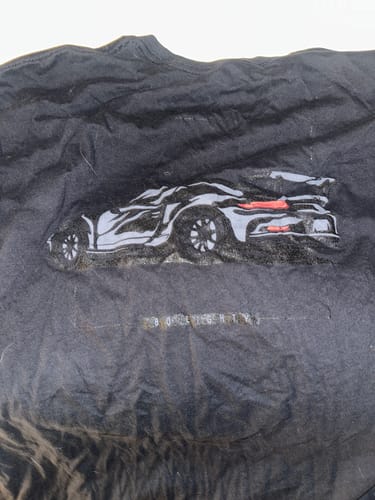 Close-up of the customer's wrinkled black DCG85 shirt showing the sports car graphic.