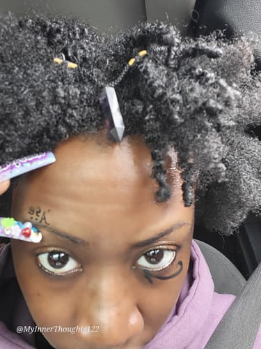 Close-up of a customer wearing a purple pointed crystal from their monthly subscription in their hair, hanging over their forehead.