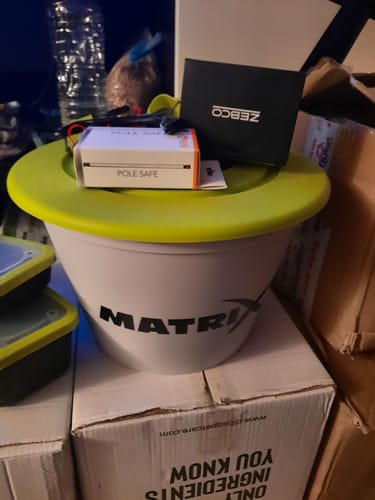 Recensent toont de witte Matrix 17L voeremmer met een groene deksel in een kamer, met andere dozen eromheen.