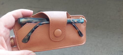 Reviewer holding the streamlined camel Skittle Sunglass Case with a pair of glasses tucked inside.