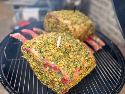 Customer's two large Tomahawk Prime Rib Roasts with a flavorful herb rub cooking on a round grill.