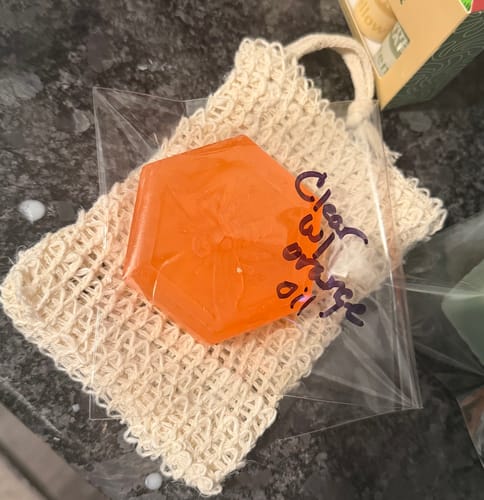 Reviewer's handmade hexagonal orange soap from the craft kit, resting in a woven pouch.