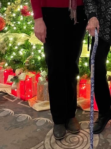 Partial view of a reviewer wearing the black Emerson Straight Leg Pants indoors next to a Christmas tree.
