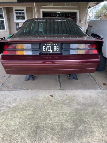 Reviewer's custom Texas Blackout Metal License Plate with 'EVIL 86' on the back of a maroon 1986 Camaro.