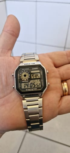 Un cliente sostiene el reloj Casio World Time Royale plateado en la palma de su mano.
