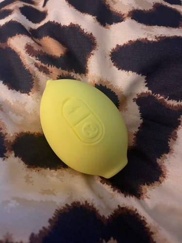 Customer's yellow Lem Clitoral Massager resting on a leopard print surface.