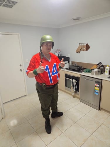 Reviewer in a full costume wearing the red Bazooka GI Joe Football Jersey, giving a thumbs-up in a kitchen.
