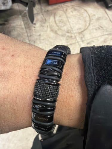 Reviewer's close-up of the personalized black bracelet on their wrist, showing multiple engraved name beads.