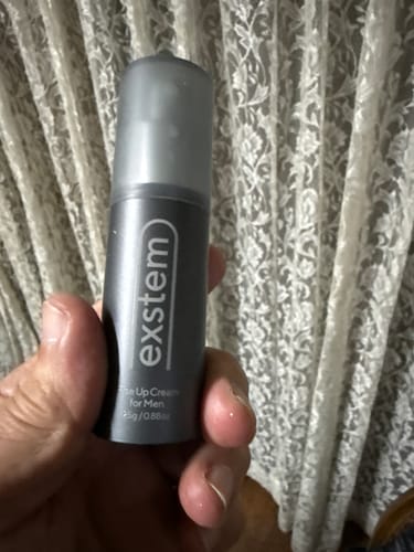 レビューアーが手に持っている、exstem（エクステム）男性用ケアクリームのボトル。