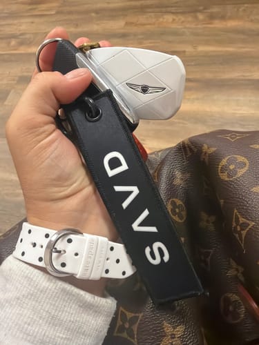 Customer holding a black fabric keychain attached to a white car key fob.