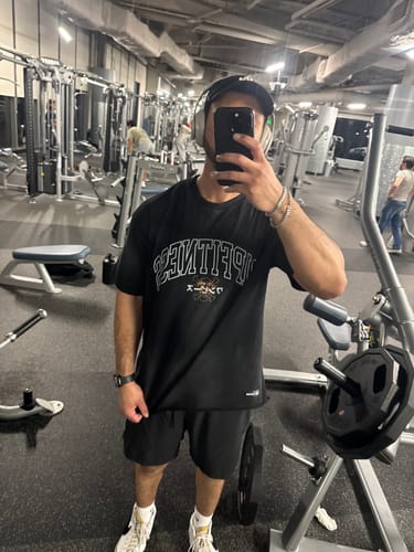Customer taking a mirror selfie in a gym wearing the black Luffy Vintage Oversized Tee, showing the front graphic and fit.