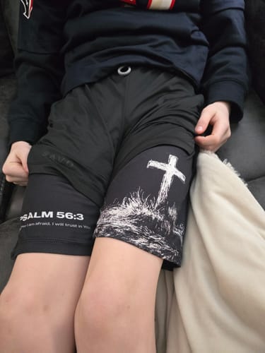 Customer's son wearing black shorts with a cross graphic on one leg and a bible verse from Psalm 56:3 on the other.