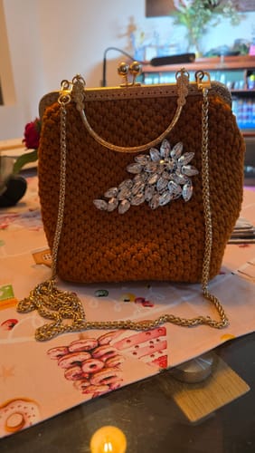 Customer's completed brown CrochetPark Lotus Handbag, shown with its gold clasp, handle, and a large crystal embellishment.