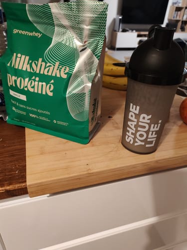 Photo d'un client montrant le sachet de Milkshake protéiné posé à côté d'un shaker sur un comptoir.