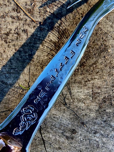 Close-up of a reviewer's shiny, polished blade with engravings, finished using the sanding belts.