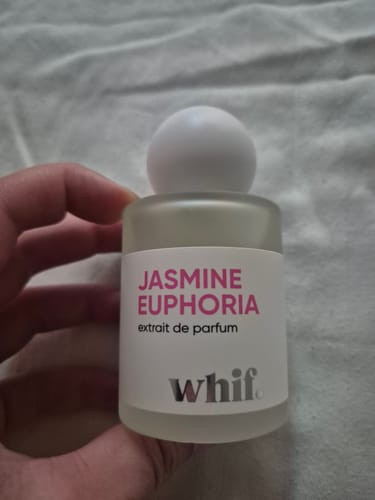 Customer holding the frosted glass bottle of Jasmine Euphoria perfume against a white fabric background.