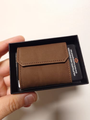 Customer holding the brown leather Nano Boy Pocket card holder wallet inside its black packaging.