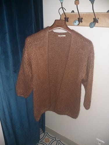Avis d'une cliente sur son gilet Prisca Camel en grosse maille, suspendu à un cintre.