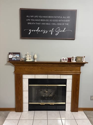 Customer's large, dark-framed Tailored Boost sign with white text mounted in their living room above a fireplace.