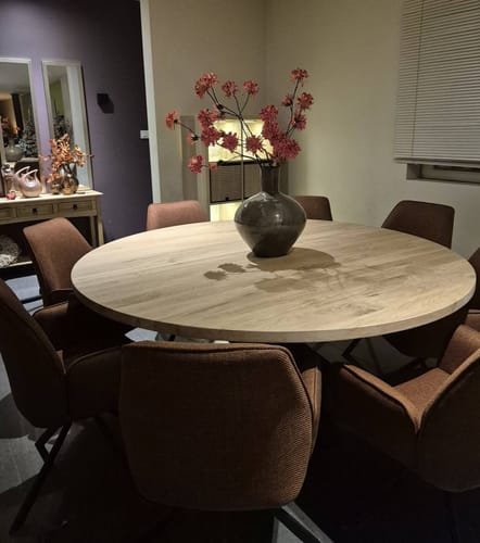 Klant toont de terra Buffy eetkamerstoelen opgesteld rond een ronde houten eettafel in een eetkamer.