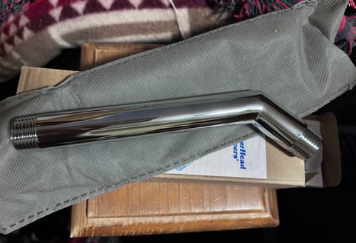 Reviewer showing the shiny, chrome-finished 7 Inch Shower Arm after unboxing.