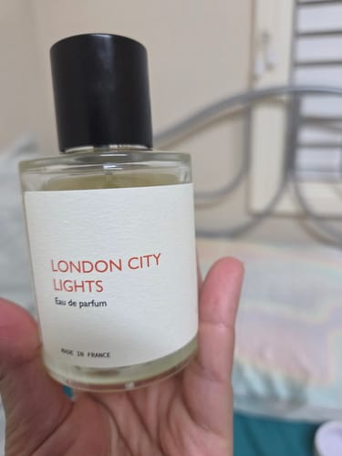 Customer holding the London City Lights perfume bottle, a clear glass bottle with a white label and black cap.