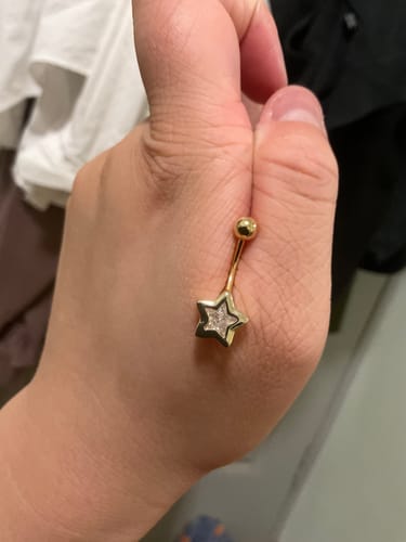 Reviewer holding the gold-plated Lucky Star Belly Bar in their hand, showing the star charm.