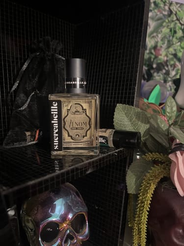 Customer's Venom perfume bottle displayed on a dark shelf with a sample bottle and an iridescent skull.
