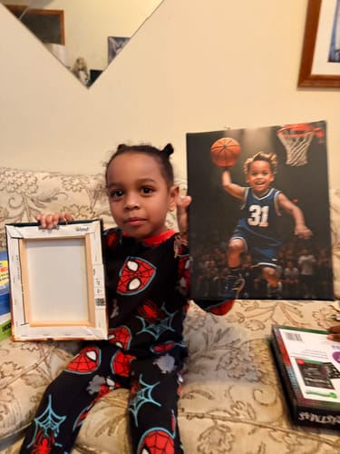 Customer's young child sits on a couch holding their personalized 'The Basketball Player' canvas portrait.