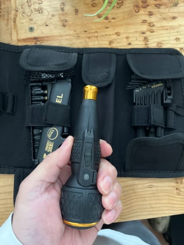 Customer holding the black and gold Vessel Tools rechargeable screwdriver in front of the open accessory kit.