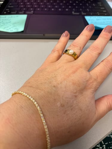 Close-up of a reviewer's hand wearing the Melly Adjustable Tennis Bracelet at a desk.