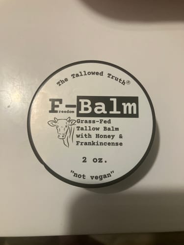 Customer's overhead view of the F-Balm tin, showing the circular label with a cow logo and product details.