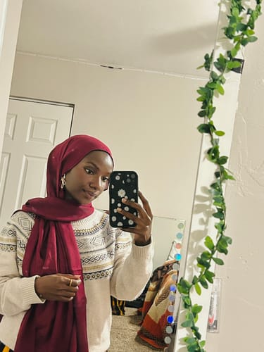 Customer taking a mirror selfie wearing a pretty, deep red hijab.