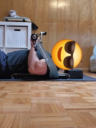 Reviewer performing a floor press with a green Harambe resistance band from the 38" Bands Bundle.