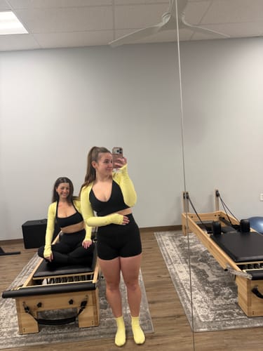 Reviewer in a pilates studio wearing the mid-length Elliosa Grip Basics socks in butter yellow.