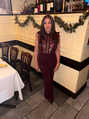 Reviewer standing in a restaurant wearing the wine-colored Vanna Crochet Flared leg Jumpsuit.