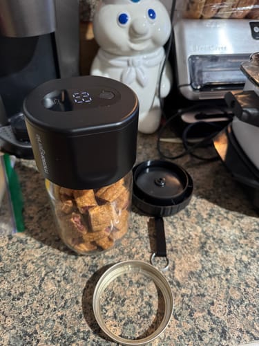 Customer's black Mason Genie Vacuum Sealer in action on a glass jar of dog treats.