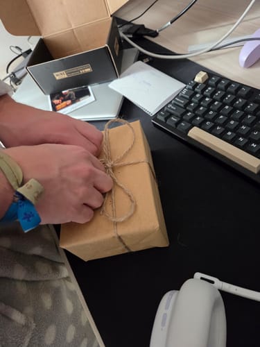 Cliente che lega con lo spago una confezione regalo marrone per il profumo Vesevo.