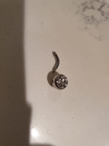 Customer's close-up of a Mini Bar Belly Ring, showing the faulty threading and loose gem.