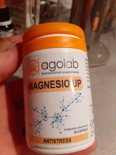 Recensore che tiene in mano il flacone bianco dell'integratore Magnesio UP con tappo arancione.