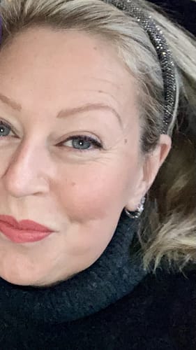 Close-up of a reviewer wearing a shiny Capsule Everluxe Hoop earring in her ear.