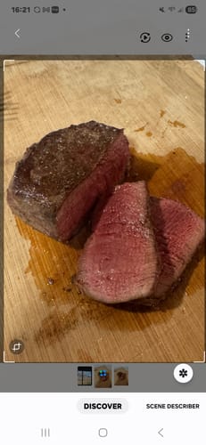 Customer's seared Filet Mignon Steak, sliced to reveal the tender pink center on a wooden board.