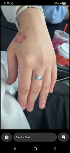 A person's hand wearing the silver 'I Am Enough Ring' on their middle finger.