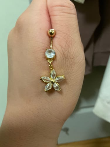 Customer holding the gold-plated Antoinetta Daisy Petal Belly Ring, showing the crystal flower charm up close in their hand.